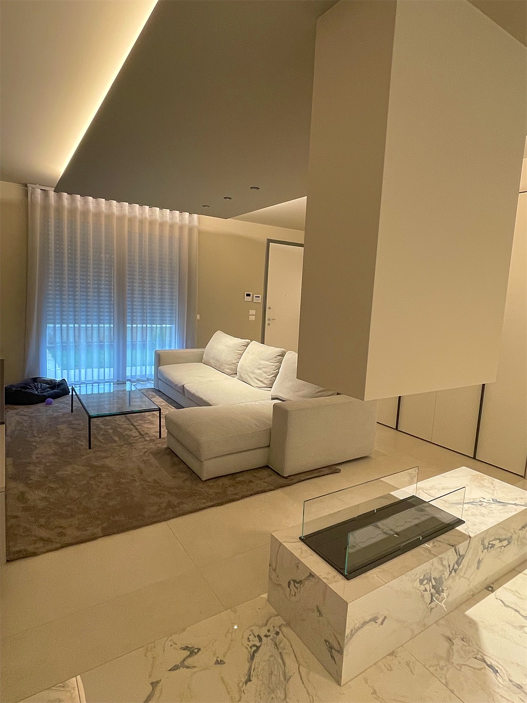 Wohnzimmer mit Sofa, Kamin und Lichtfuge in der Decke